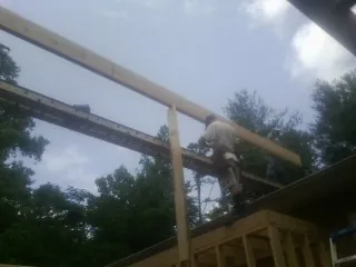 Carpenter setting a ridge beam over a new addition frame — Ice Dam Removal by Roofing Brothers in Morganton