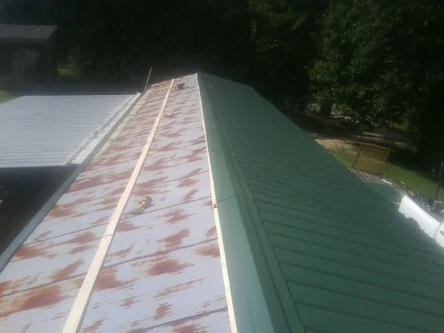 Old rusted panels beside newly installed green metal roofing — Wind Damage Roof Repair by Roofing Brothers in Morganton