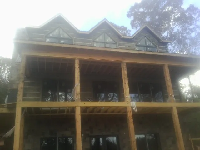 Dormers and porch framing on a large log home under construction — Roof Coating work by our crew in Morganton
