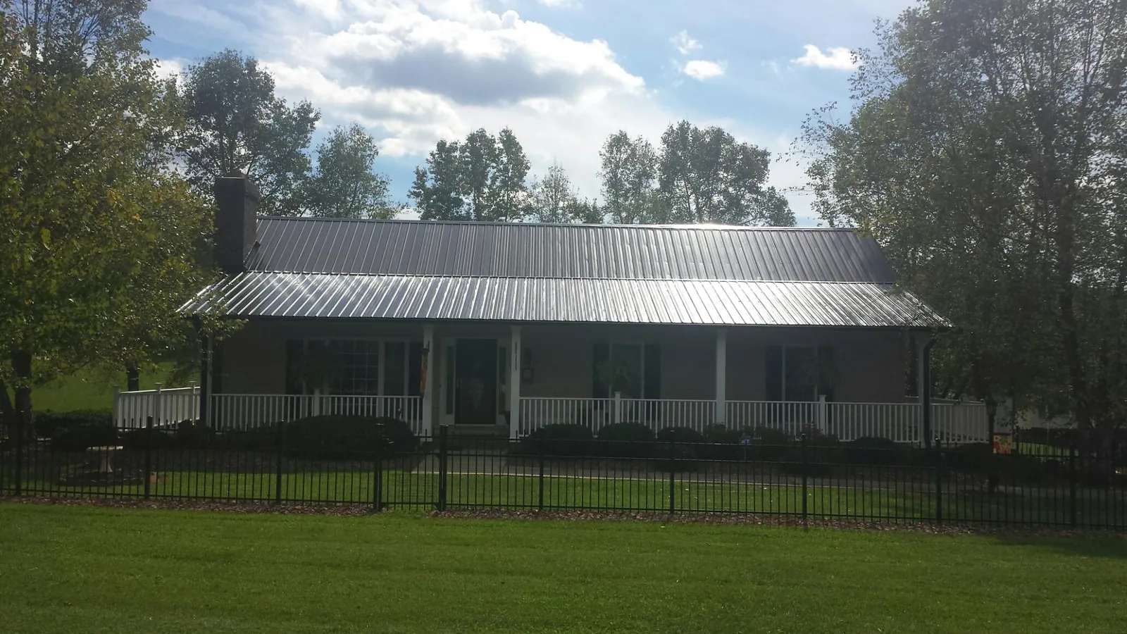 Gray metal roof on a brick ranch with a full width front porch — Gutter Guard Installation work by our crew in Morganton