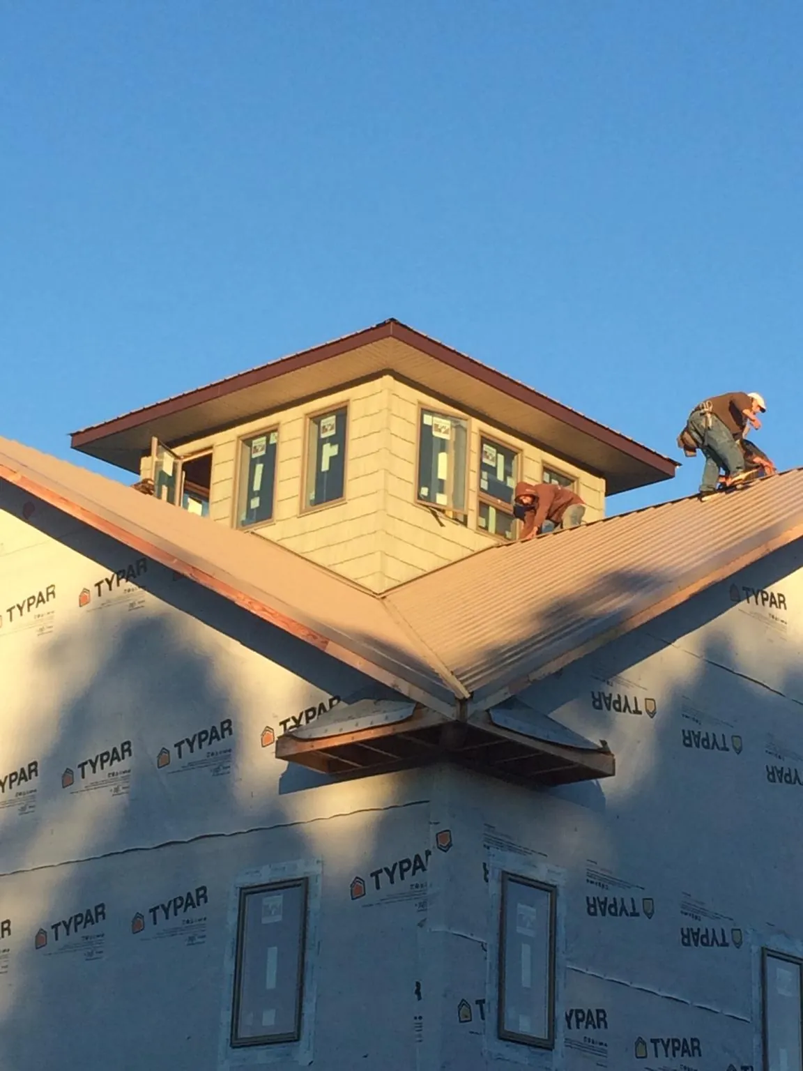 Roofers working around a rooftop cupola on a new metal roof at sunset — Roof Waterproofing in Morganton by Roofing Brothers